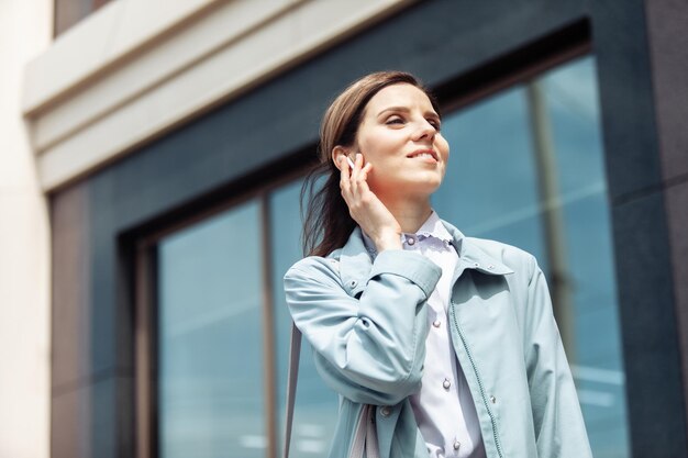 Ritratto di una bella signora con cuffie wireless in città