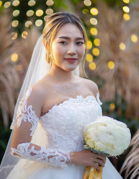 Ritratto di una bella sposa asiatica in abito da sposa bianco con un bouquet da sposa