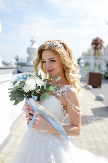 Ritratto di una bella sposa bionda con un mazzo di fiori.