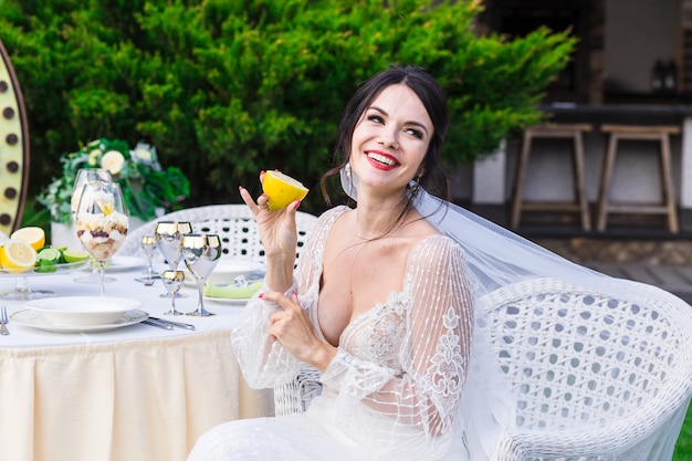 Ritratto di una bella sposa che mangia limone sulla cerimonia di matrimonio.