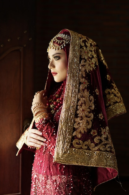 Ritratto di una bella sposa indiana in abito rosso e oro