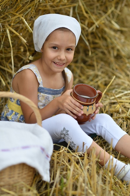 Ritratto di una bellissima bambina con latte in campo in estate