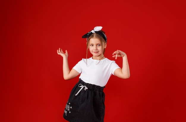 Ritratto di una bellissima bambina in posa su uno sfondo rosso isolato.