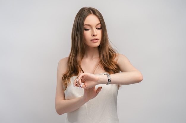 Ritratto di una bellissima donna che guarda l'orologio che controlla l'ora isolata sullo sfondo