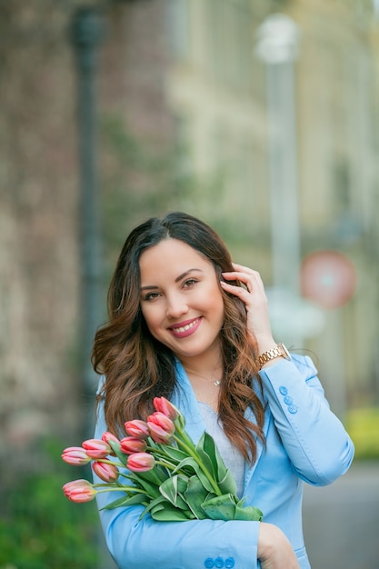 Ritratto di una bellissima giovane donna in abito blu con un mazzo di tulipani