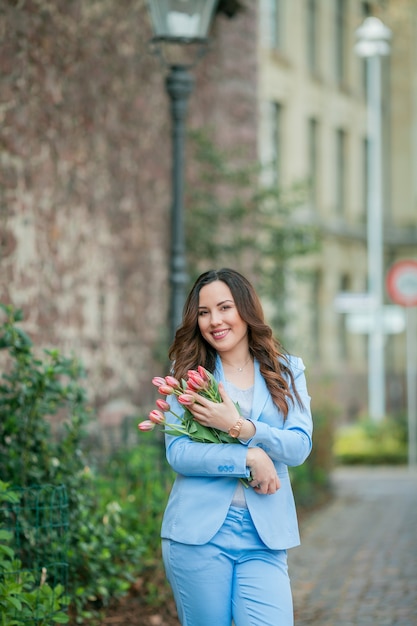 Ritratto di una bellissima giovane donna in abito blu con un mazzo di tulipani