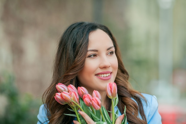 Ritratto di una bellissima giovane donna in abito blu con un mazzo di tulipani