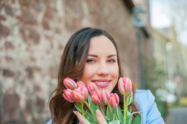 Ritratto di una bellissima giovane donna in abito blu con un mazzo di tulipani