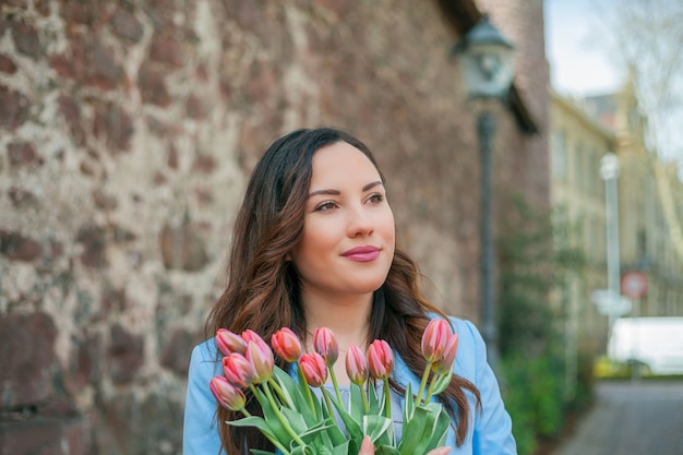 Ritratto di una bellissima giovane donna in abito blu con un mazzo di tulipani