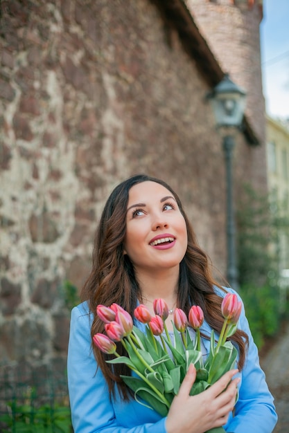 Ritratto di una bellissima giovane donna in abito blu con un mazzo di tulipani