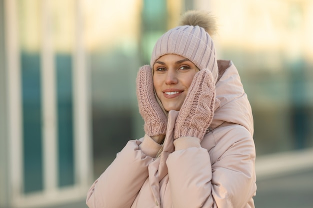 Ritratto di una bellissima giovane modella in rosa cappello lavorato a maglia e guanti. Bella giovane donna bionda sorridente naturale che indossa i guanti tricottati.