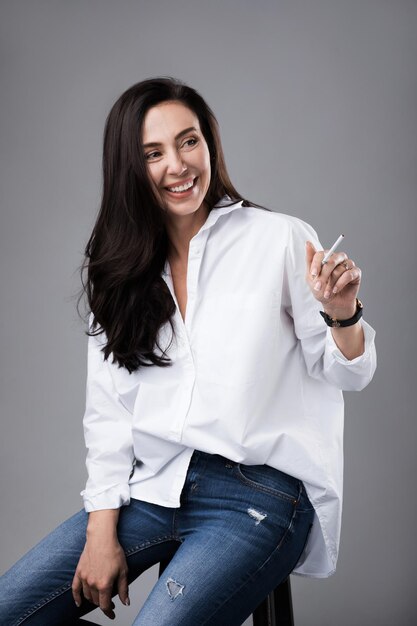 Ritratto di una bellissima modella di mezza età che indossa una camicia bianca e jeans in uno studio fotografico