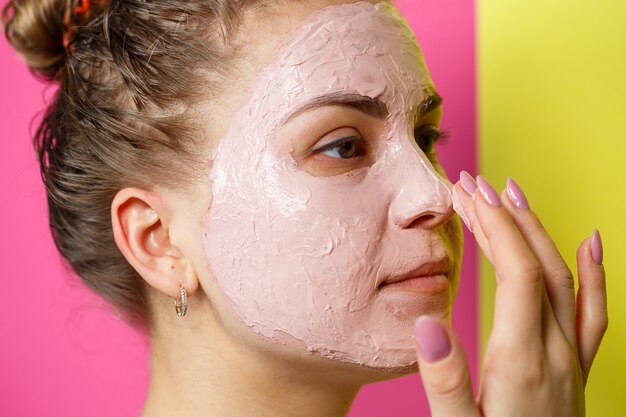 Ritratto di una bellissima ragazza che si mette una maschera rinfrescante sul viso per ringiovanire e tonificare la pelle. Trattamenti di bellezza