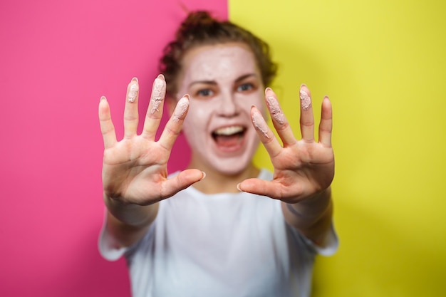 Ritratto di una bellissima ragazza che si mette una maschera rinfrescante sul viso per ringiovanire e tonificare la pelle. Trattamenti di bellezza