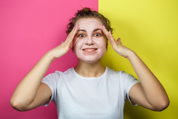 Ritratto di una bellissima ragazza che si mette una maschera rinfrescante sul viso per ringiovanire e tonificare la pelle. Trattamenti di bellezza