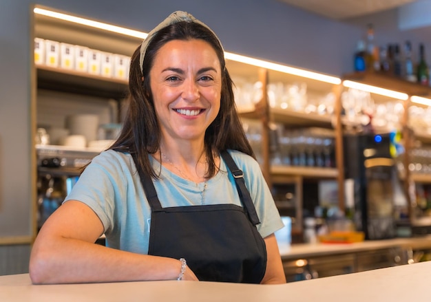 Ritratto di una cameriera graziosa e sorridente con la macchina del caffè sullo sfondo vengono rimosse le restrizioni covid e viene tolto l'uso obbligatorio delle mascherine