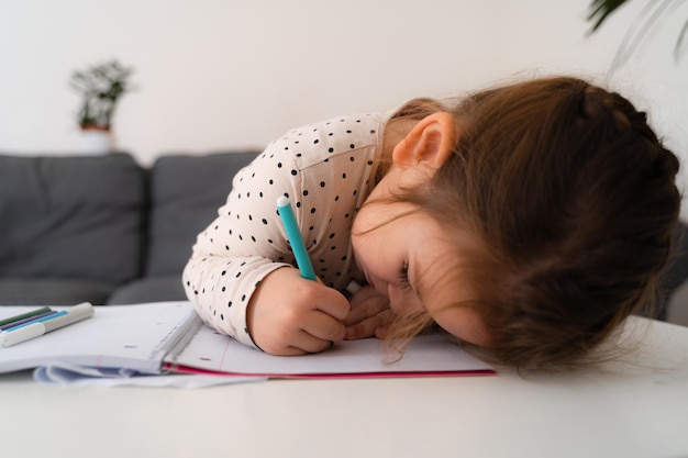 Ritratto di una carina bambina in età prescolare che disegna con le matite a casa mentre è seduta