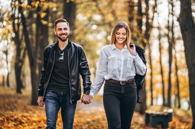 Ritratto di una coppia amorosa felice che cammina all'aperto nel parco di autunno