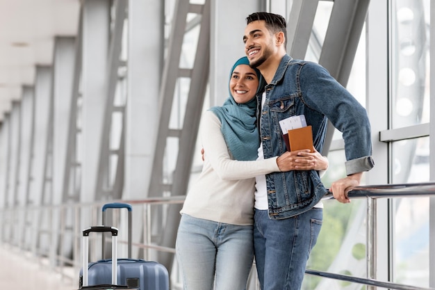 Ritratto di una coppia islamica allegra in attesa del volo al terminal dell'aeroporto