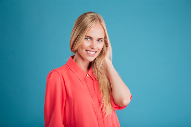 Ritratto di una donna abbastanza sorridente in abito rosso che guarda davanti isolato su un muro blu