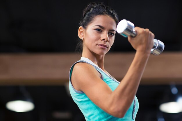 Ritratto di una donna affascinante allenamento con manubri in palestra