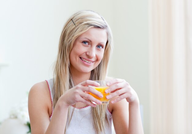 Ritratto di una donna allegra che beve un succo d&#39;arancia