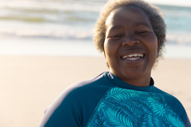 Ritratto di una donna anziana afroamericana felice con i capelli corti grigi contro il paesaggio marino durante il tramonto. Pensione, sorriso, inalterato, stile di vita, vacanze, divertimento e concetto di natura.