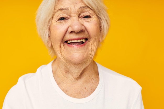 Ritratto di una donna anziana amichevole in tshirt casual gesti con le mani su sfondo giallo