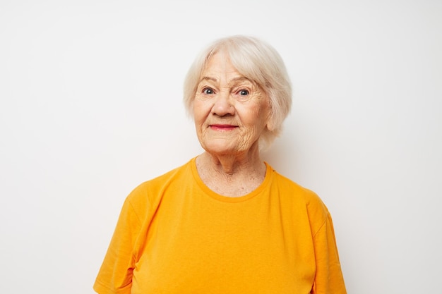 Ritratto di una donna anziana amichevole in una maglietta gialla in posa vista ritagliata