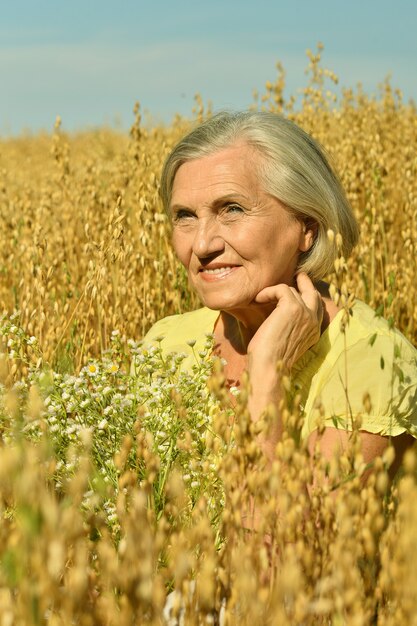 Ritratto di una donna anziana con fiori in campo