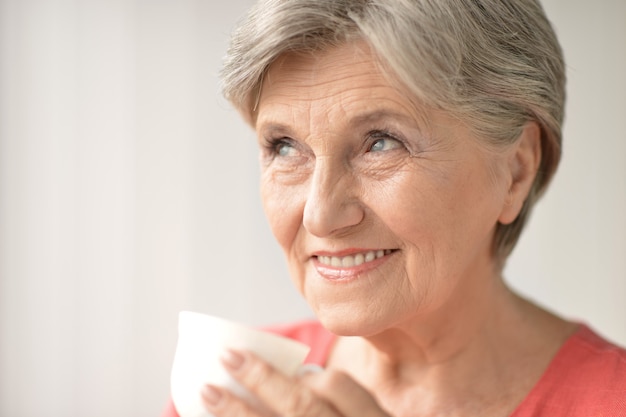 Ritratto di una donna anziana con una tazza a casa
