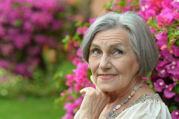 Ritratto di una donna anziana in passeggiata con fiori rosa