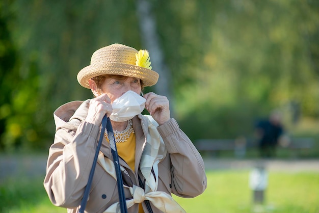 Ritratto di una donna anziana positiva che indossa una maschera a causa dello stile di vita coronavirus degli anziani pensionati nelle vacanze estive