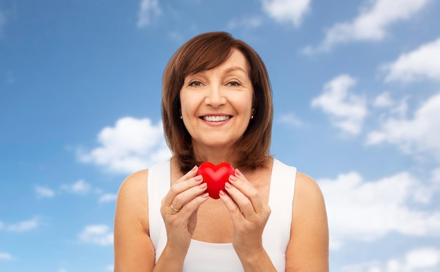 ritratto di una donna anziana sorridente con un cuore rosso