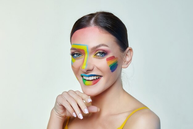 Ritratto di una donna attraente con trucco luminoso con bandiera arcobaleno LGTB