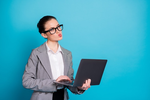 Ritratto di una donna attraente e intelligente, specialista IT che tiene in mano un laptop che crea un'idea isolata su uno sfondo di colore blu brillante