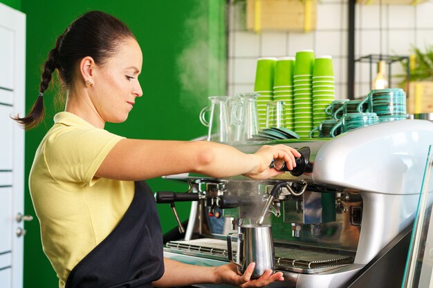 Ritratto di una donna barista nella caffetteria in piedi al bancone