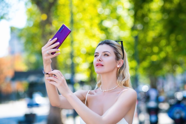 Ritratto di una donna bionda con un cellulare. Una ragazza carina parla al cellulare.