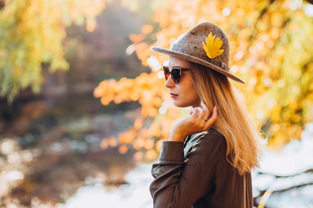 Ritratto di una donna bionda in occhiali da sole nella foresta di autunno