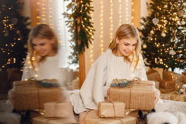 Ritratto di una donna bionda seduta vicino all'albero di Natale con due yorkshire terrier