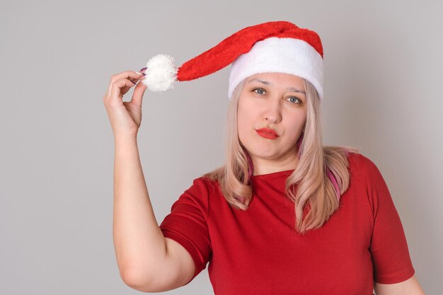 Ritratto di una donna bionda sexy anni '40 con un cappello da Babbo Natale su sfondo grigio