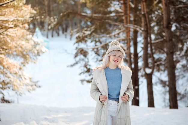 Ritratto di una donna bionda sorridente allegra che trascorre del tempo all'aperto in inverno nella foresta