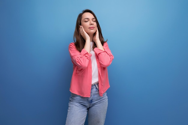 Ritratto di una donna calma con capelli castano scuro in jeans con orecchie coperte in posa in studio