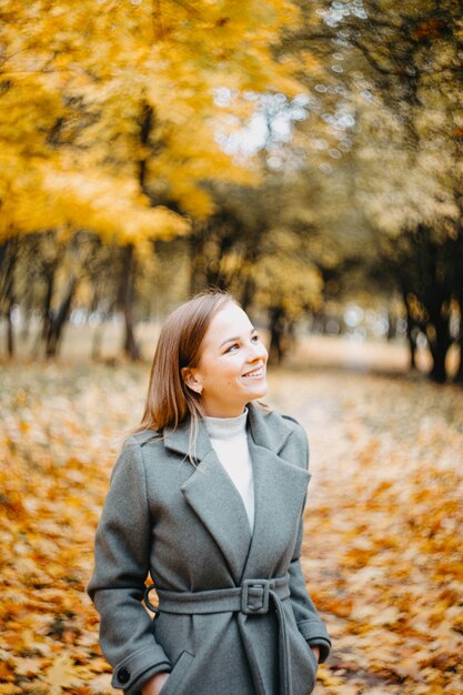 Ritratto di una donna carina in autunno che cammina nel parco autunnale