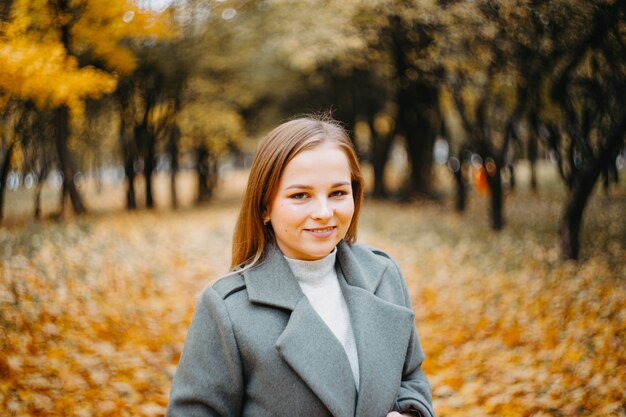 Ritratto di una donna carina in autunno che cammina nel parco autunnale