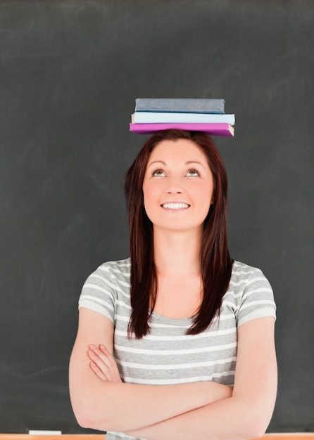 Ritratto di una donna carina smilling bilanciamento libri sulla sua testa