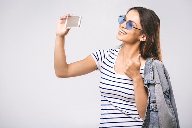 Ritratto di una donna carina sorridente in occhiali da sole facendo selfie foto sullo smartphone
