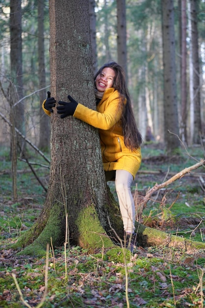 Ritratto di una donna che abbraccia un albero nella foresta