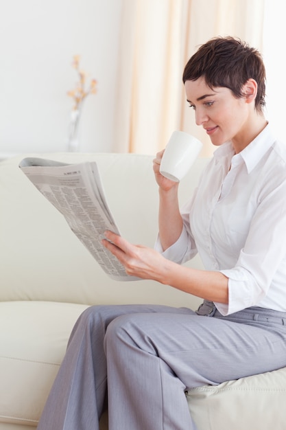 Ritratto di una donna che beve caffè durante la lettura delle notizie