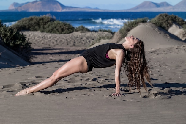 Ritratto di una donna che fa yoga sulla spiaggia